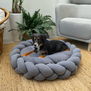 Black dog resting on Charcoal Grey Large Round Plush Pet Bed with Braided Knit Border and Aesthetic Design
